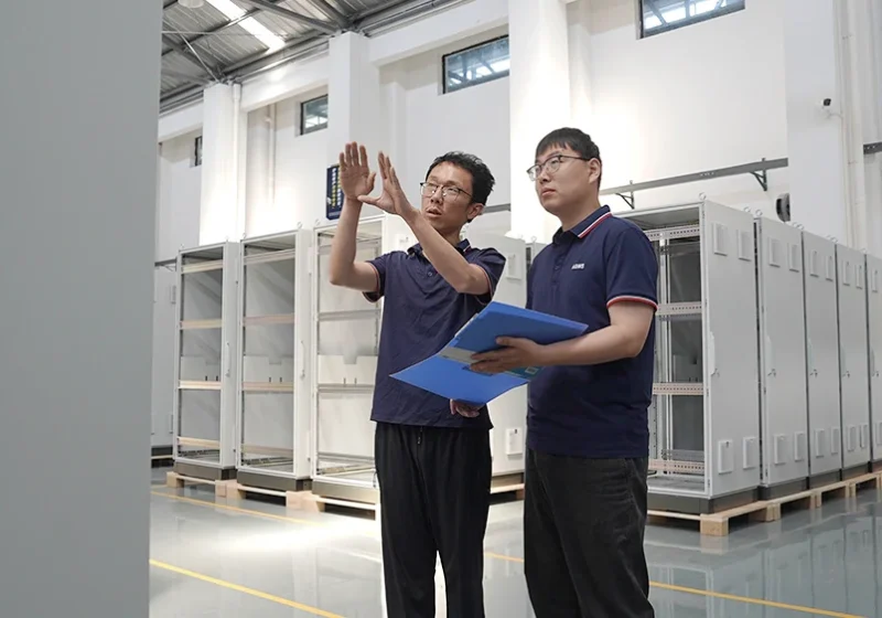 Two ADMS engineers checking a cabinet build against the drawings